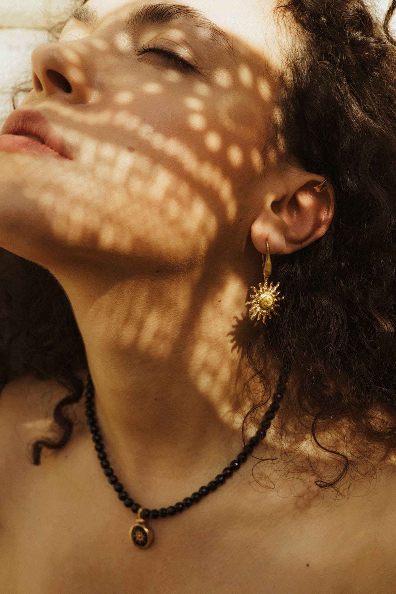 Kobieta prezentująca zloty kolczyk w kształcie słońca